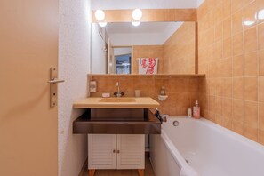 A bathroom with a sink, mirror, and bathtub.