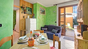 Un coin repas avec une table dressée pour deux personnes, un canapé et une vue sur l’extérieur.