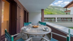 Una terraza de madera con una mesa redonda, sillas y un plato de comida.