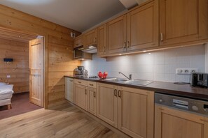 Una cocina moderna con armarios de madera, un lavamanos de acero inoxidable y un lavavajillas Siemens.