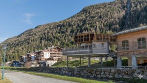 Un complejo turístico de montaña con edificios de madera, un muro de piedra y un letrero que dice 'Telecazina de Vallorcín'.