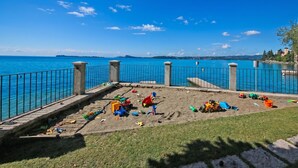 A sandy play area with toys and a view of the sea. - Roby loft-Direct Lake Access/Beach, Gardone Riviera, Italy (Gardone Riviera)