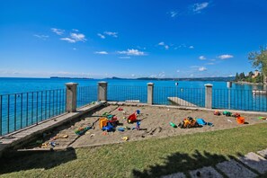 A sandy play area with toys and a view of the sea.