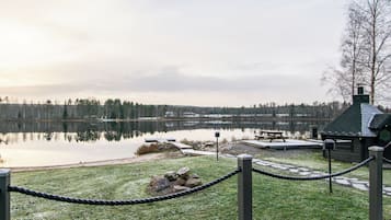 A lakeside view with a wooden dock, picnic area, and a cabin.