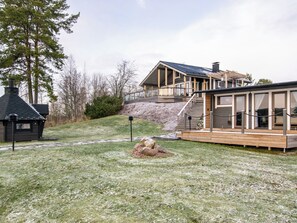 Une maison moderne dotée d’une terrasse, d’un petit chalet et d’une cour gazonnée.