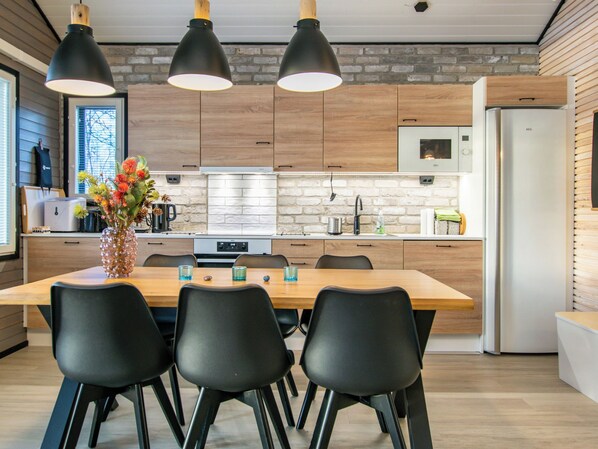 Une cuisine moderne avec des meubles en bois, un îlot central doté de chaises et des luminaires suspendus.