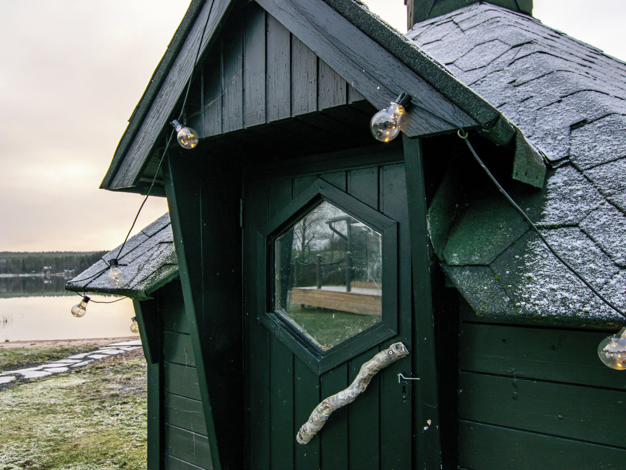 Une structure en bois peinte en vert, dotée d’une fenêtre en forme de losange et d’une poignée de porte.