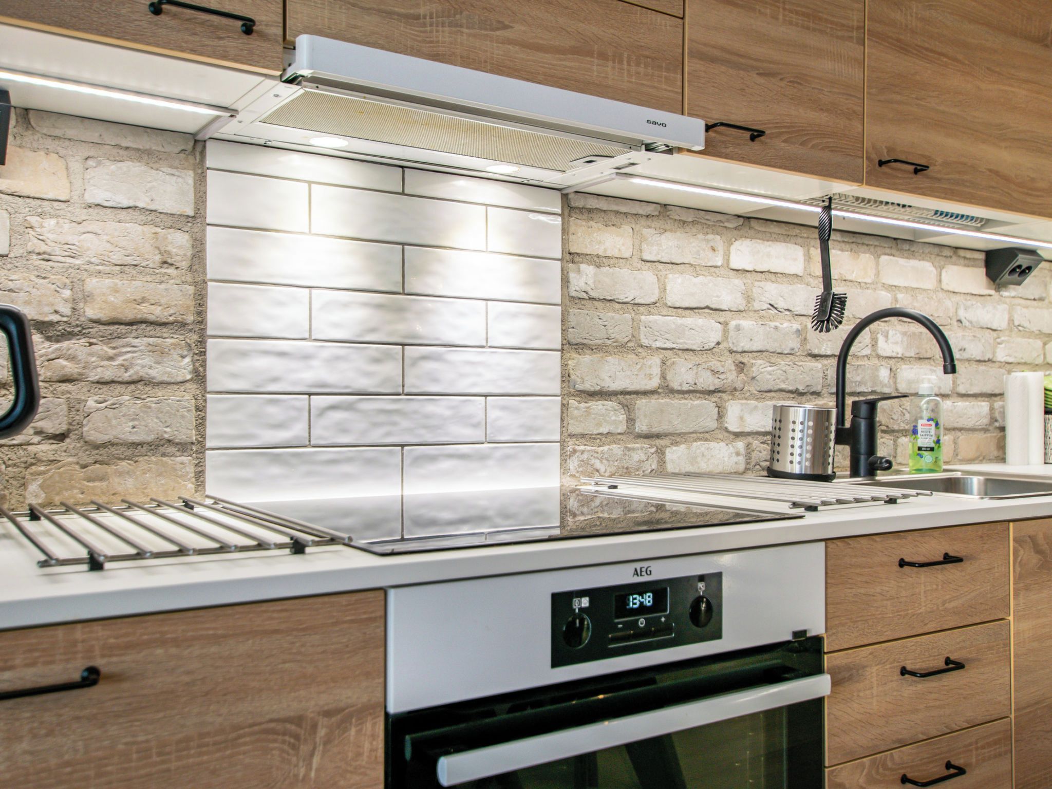 Une cuisine moderne avec un mur de fond en briques, des appareils électroménagers en acier inoxydable et des armoires en bois.