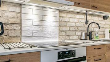 Une cuisine moderne avec un mur de fond en briques, des appareils électroménagers en acier inoxydable et des armoires en bois.