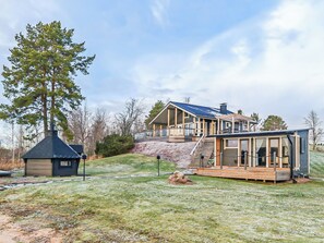 A modern house with a large deck, a garage, and a covered outdoor area.