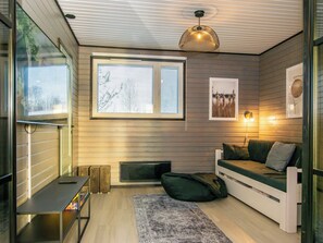Ein gemütliches Zimmer mit einem Bett, einem kleinen Tisch, einem Fenster mit Jalousien und einer Wandleuchte.