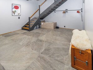 Une pièce avec un escalier, une affiche accrochée au mur et une commode recouverte de fourrure.