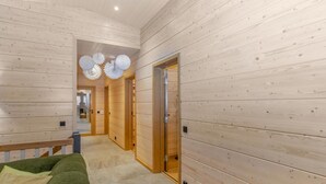 Un interno moderno con pareti in legno, un divano verde e un corridoio che conduce a un'altra stanza.