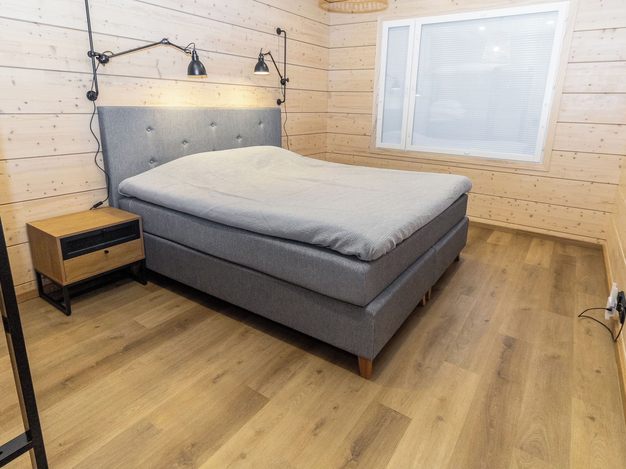 A bedroom with a bed, bedside table, lamp, and window.