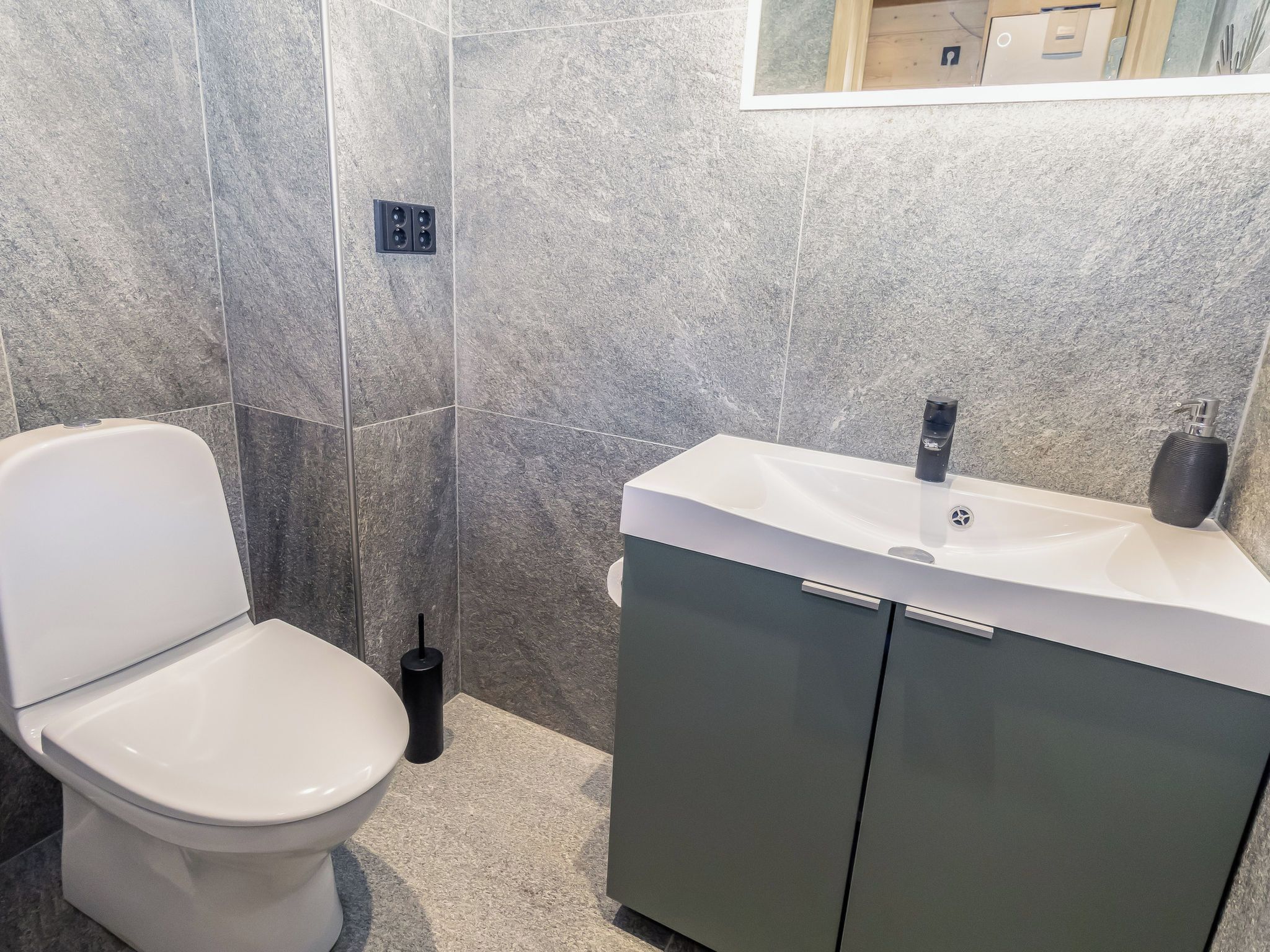 Un baño con inodoro, lavamanos y espejo.
