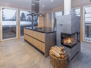 Una cocina moderna con una isla central, una chimenea empotrada y amplias ventanas.