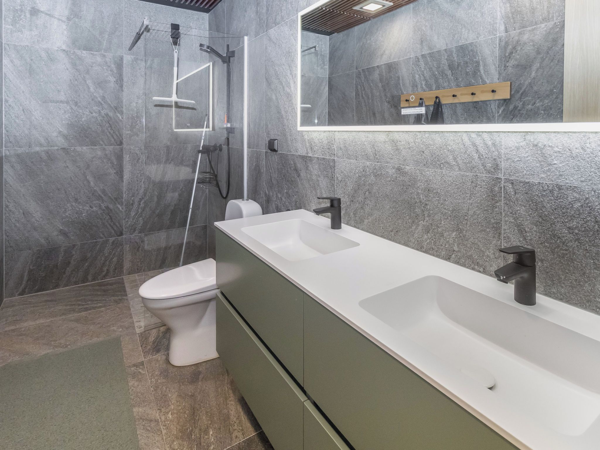 A modern bathroom with a shower, toilet, and dual sinks.
