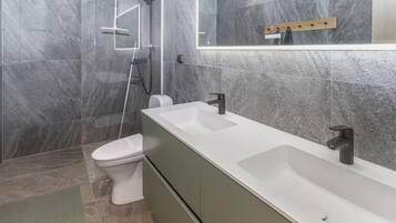 A modern bathroom with a shower, toilet, and dual sinks.