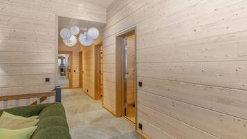 A hallway with wooden walls and a green sofa with cushions.