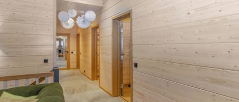 En hall med träpanel på väggarna och en grön soffa med kuddar.