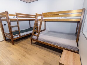 A room with two bunk beds, wooden flooring, and a small wooden table. - Satukero by Interhome (Pelkosenniemi)