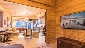 Interior acogedor de una cabaña de madera con comedor, cocina y un gran ventanal con vistas panorámicas.