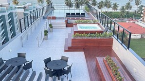 Una terraza en la azotea con piscina, zonas de estar y vistas al océano.