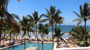 Une vue sur la piscine, avec des palmiers et une plage en arrière-plan.