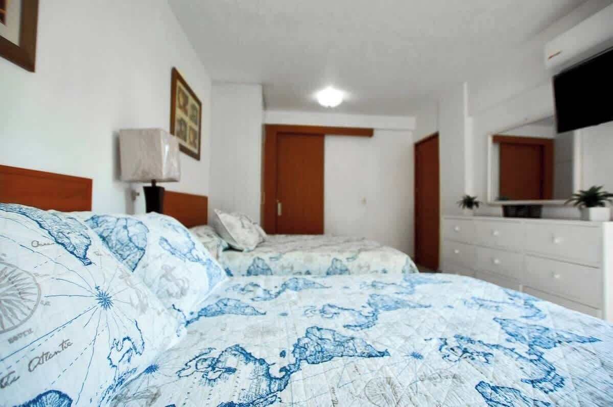 Una camera da letto con due letti, una cassettiera, uno specchio e una porta.