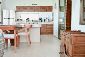 A modern kitchen with wooden cabinets, a central island, and a dining area with chairs.