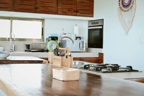 A kitchen with a wooden countertop, a gas stove, a sink, and wooden cabinets.