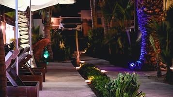 Un espace extérieur aménagé pour la nuit, avec un chemin, des sièges et des plantes.