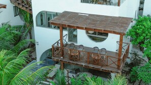 Una terraza al aire libre de varios niveles, con barandas de madera y asientos, rodeada de exuberante vegetación.