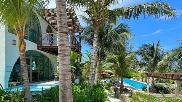 A resort with a pool, palm trees, and a building with a balcony. - Villa · Private Pool · Ocean View · Isla Mujeres (Isla Mujeres)