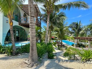 A resort with a pool, palm trees, and a building with a balcony. - Villa · Private Pool · Ocean View · Isla Mujeres (Isla Mujeres)