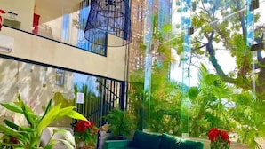 Een modern interieur met een groene bank, potplanten en een groot raam met uitzicht op groen.
