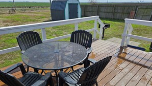 Una terraza cubierta al aire libre con una mesa redonda y cuatro sillas, rodeada por una barandilla blanca.