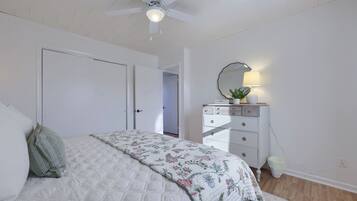 A bedroom with a bed, a dresser, a ceiling fan, and a mirror.