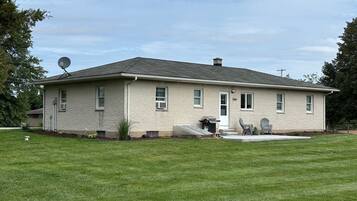 A single-story house with a front porch, a satellite dish, and a lawn.