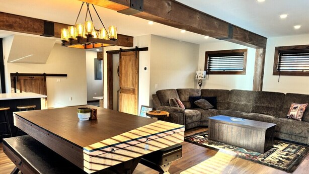 A modern living room with a wooden dining table, a sofa, and a coffee table. - New Construction Barn style- Minutes from Skiing and Lakes (Wilmington)