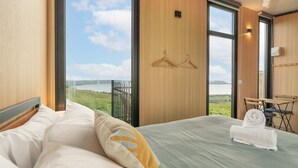 Habitación de hotel con una cama grande, vistas a un lago y un pequeño escritorio con silla.