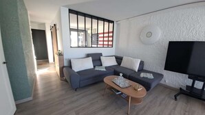 Ein modernes Wohnzimmer mit einem Ecksofa, einem Couchtisch und einem Flachbildfernseher.