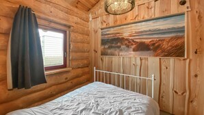 A wooden cabin room with a bed, a window with curtains, and a painting on the wall. - 3 bedroom lovely home in Den Oever (Den Oever)