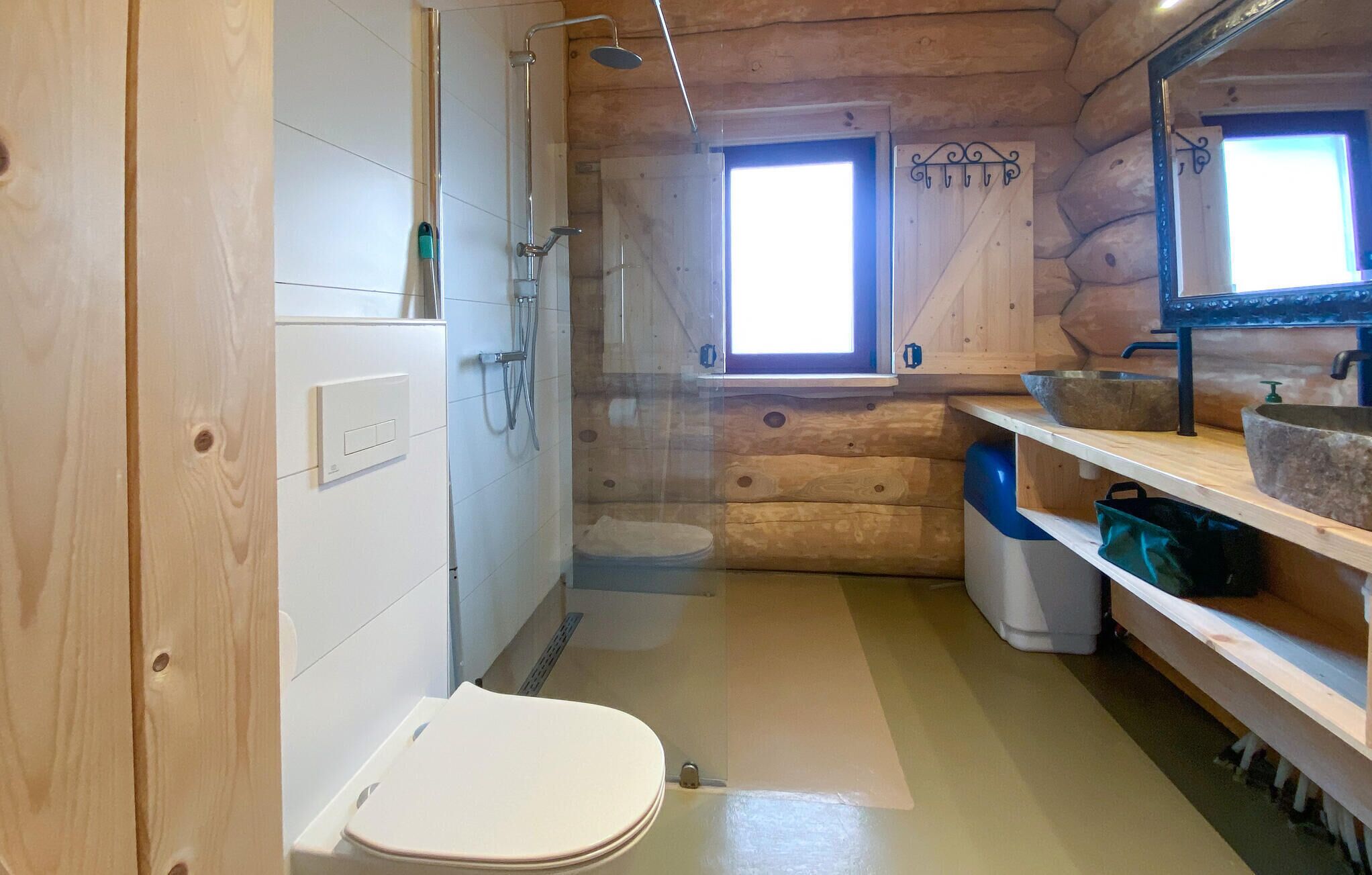 Een houten badkamer in een vakantiehuis, met toilet, douche en wastafel.