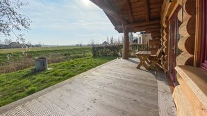 A wooden deck with a view of a green field and a distant building. - 3 bedroom lovely home in Den Oever (Den Oever)