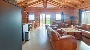 A spacious living area with a large sofa, a coffee table, and a dining table with chairs. There are large windows providing natural light and a view of the outdoors. - 3 bedroom lovely home in Den Oever (Den Oever)