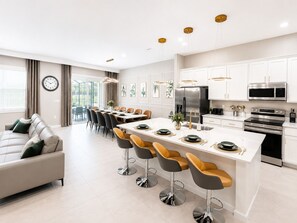 A modern kitchen with white cabinets, stainless steel appliances, and a central island with bar stools.