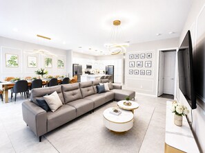 Een moderne woonkamer met een modulaire bank, een ronde salontafel en een flatscreen televisie.