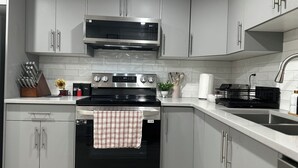 A modern kitchen with grey cabinets, a black stove, and stainless steel appliances. - Entire guest suite in Calgary (Calgary)