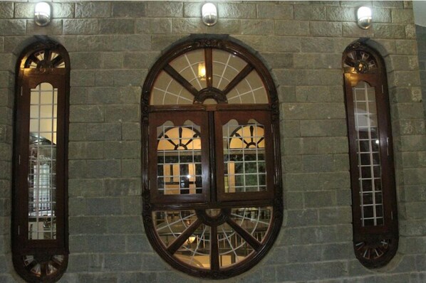 Un mur de pierre orné de trois fenêtres en arc, chacune présentant un motif à carreaux et un motif circulaire central.